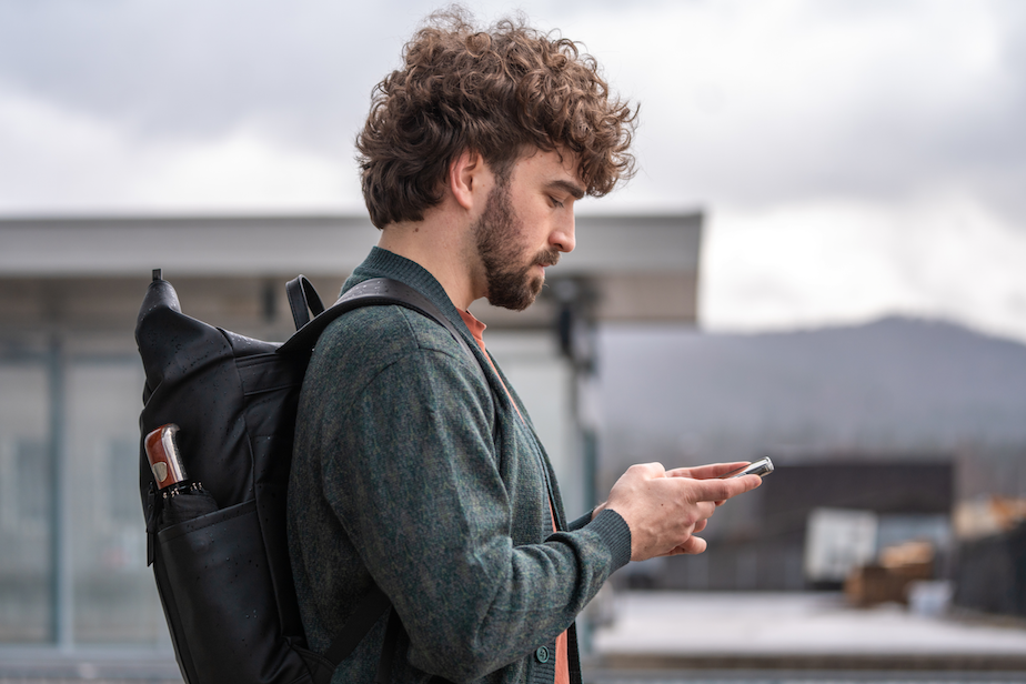 A lonely young man holds a smartphone.